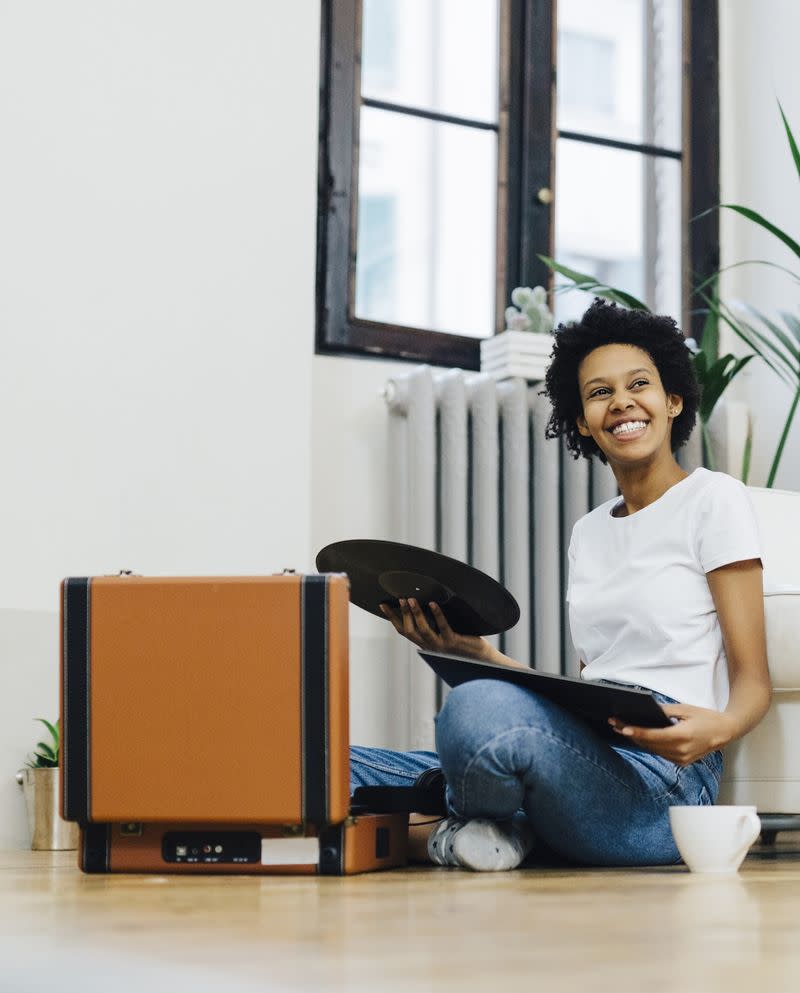 A woman sitting on the floor listening to records