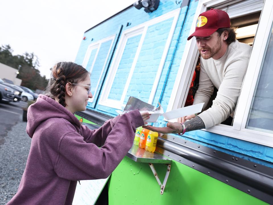 Austin Bickford of Raynham, owner of Augie's Food Truck in Lakeville, serves Hope LaLiberte, 17, on Saturday, Jan. 27, 2024.