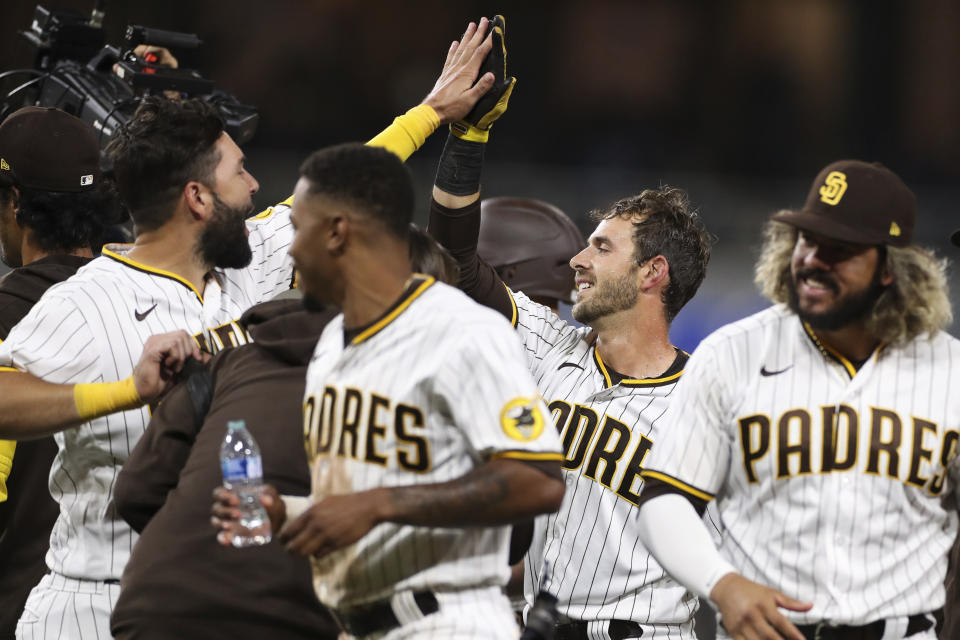San Diego Padres' Austin Nola, second from right, is congratulated by Eric Hosmer, left, after driving in the winning run against the Los Angeles Dodgers in the 10th inning of a baseball game Saturday, April 23, 2022, in San Diego. (AP Photo/Derrick Tuskan)