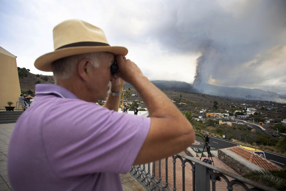 A man looks out towards the eruption of a volcano near El Paso on the island of La Palma in the Canaries, Spain, Monday, Sept. 20, 2021. Lava continues to flow slowly from a volcano that erupted in Spain's Canary Islands off northwest Africa. Officials say they are not expecting any other eruption and no lives are currently in danger. (AP Photo/Gerardo Ojeda)