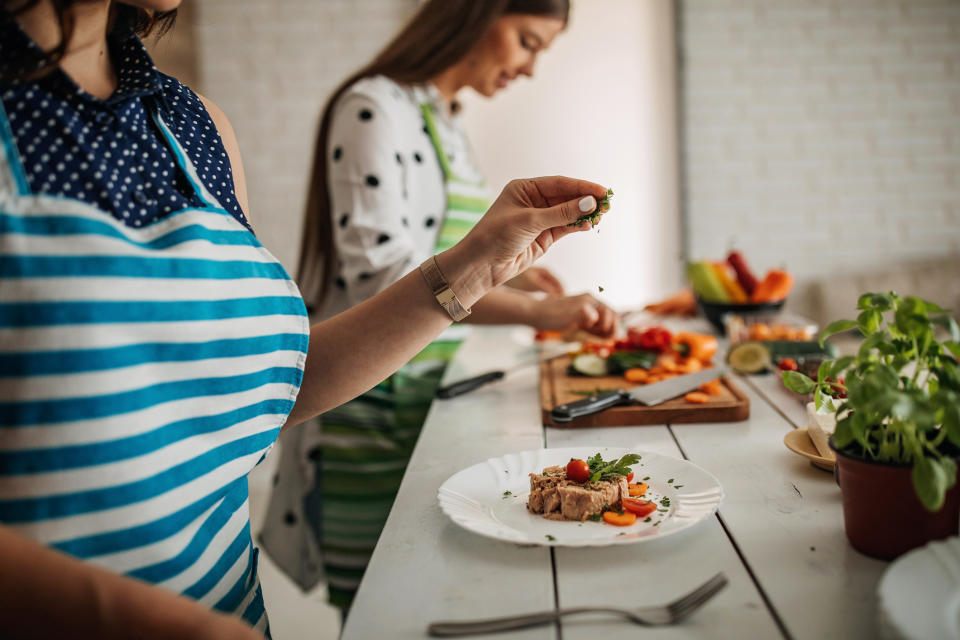 Two women serving dinner in the kitchen, as Brits are unsure about portion sizes. (Getty Images)