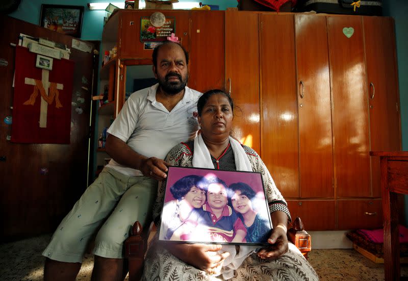 Karibeeran Paramesvaran and his wife Choodamani, who had lost three children in the 2004 tsunami, pose with a photograph showing their children inside their house that they have turned into a care home for orphaned children in Nagapattinam district in the