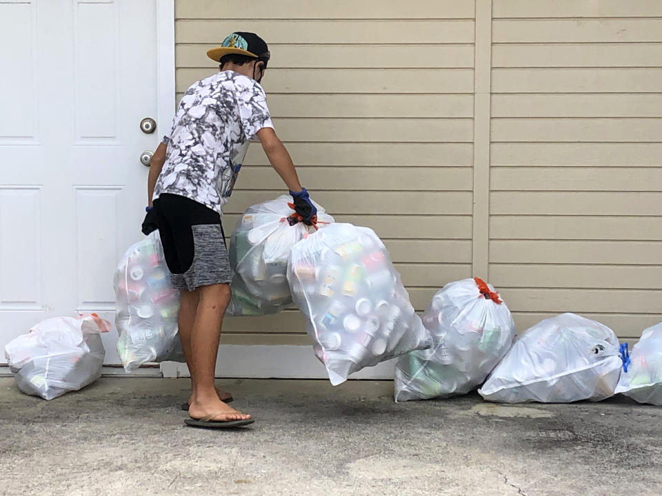 In this April 2021 photo provided by Maria Price, Genshu Price collects recyclable cans and bottles for his fundraiser, Bottles4College, in Hau'ula, Hawaii. Price started Bottles4College three years ago to raise money for his own tuition but has since expanded the recycling project to benefit other students. (Bottles4College via AP)