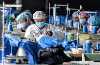 Workers make protective suits at a factory of a medical equipment maker in Urumqi, Xinjiang