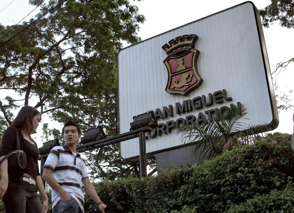 File Photo: Filipino pedestrians walk past the San Miguel corporation headquarter in Manila, Philippines. (Photo: JOEL NITO/AFP via Getty Images)