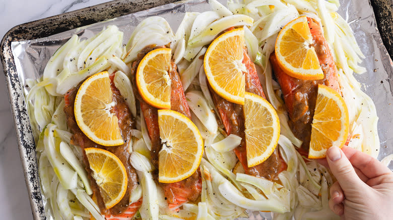 hand topping salmon with fresh orange slices