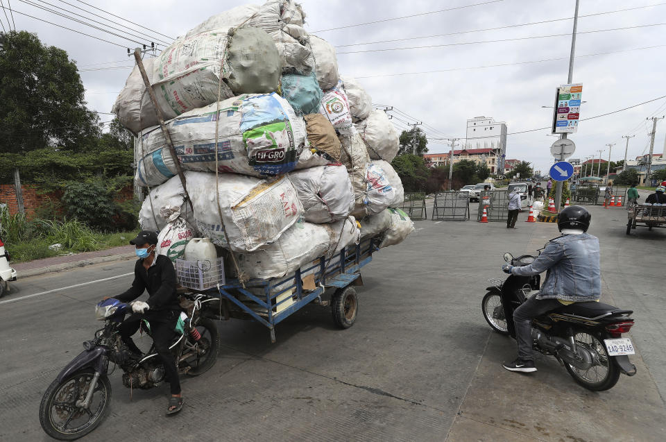 A man transporting huge bags of recyclables is turned back at a blocked street in a zone where the COVID-19 cases are rising sharply in Stung Meanchey complex outside Phnom Penh, Cambodia, Friday, May 7, 2021. Cambodia on Thursday eased a major restriction it had imposed to battle a major coronavirus outbreak, allowing travel in and out of the capital Phnom Penh and the satellite town of Takhmao. The travel ban has been in effect for three weeks so far. (AP Photo/Heng Sinith)