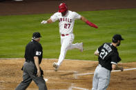Los Angeles Angels' Mike Trout, center, scores on a single by Justin Upton as Chicago White Sox starting pitcher Lucas Giolito, right, covers the plate and home plate umpire Larry Vanover watches during the fourth inning of an Opening Day baseball game Thursday, April 1, 2021, in Anaheim, Calif. (AP Photo/Mark J. Terrill)