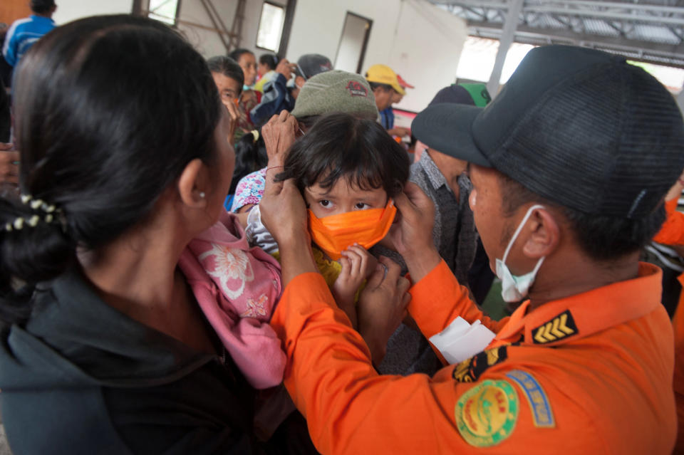 An disaster management agency officer places a mask on child at a shelter for volcano evacuees on Saturday.&nbsp;