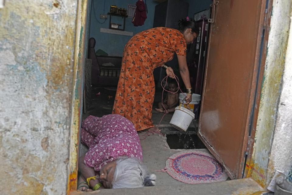 A resident of Ambedkar Nagar, a low-income settlement in the shadows of global software companies in Whitefield neighborhood, draws water from a sump inside her house in Bengaluru, India, Monday, March 11, 2024. Bengaluru is witnessing an unusually hot February and March, and in the last few years, it’s received little rainfall in part due to human-caused climate change. (AP Photo/Aijaz Rahi)