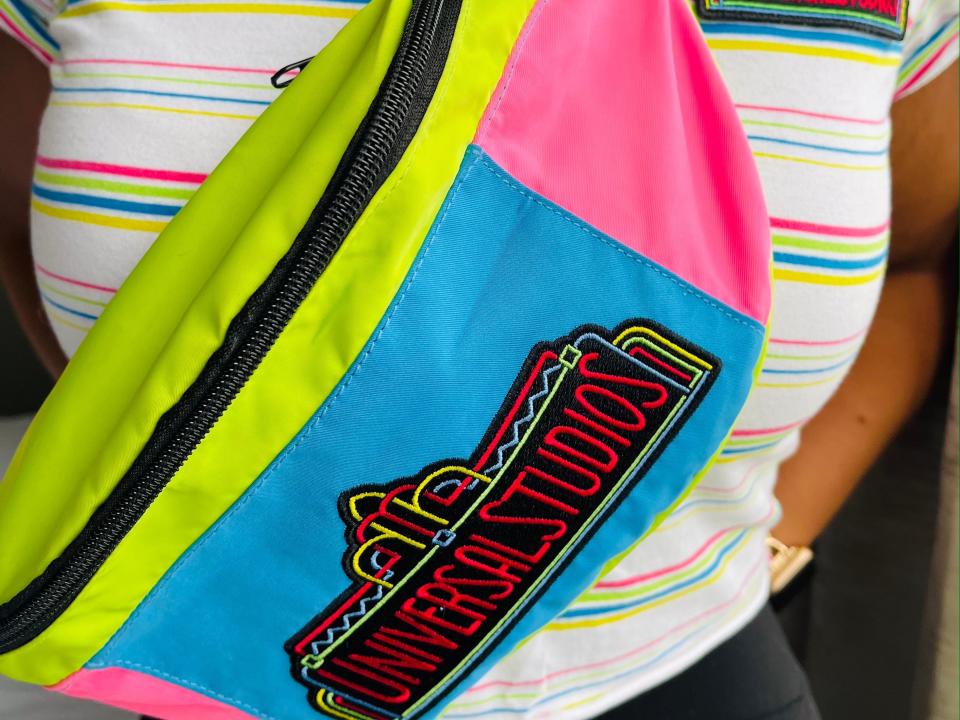 Carly Caramanna wearing universal studios shirt and neon fanny pack