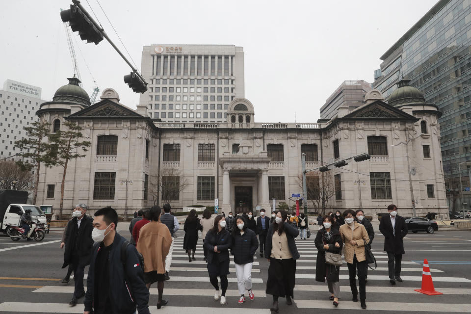 People wearing face masks walk by the headquarters of the Bank of Korea in Seoul, South Korea, Thursday, March 4, 2021. South Korea's central bank says the country's economy shrank for the first time in 22 years in 2020 as the coronavirus pandemic destroyed service industry jobs and depressed consumer spending. (AP Photo/Ahn Young-joon)