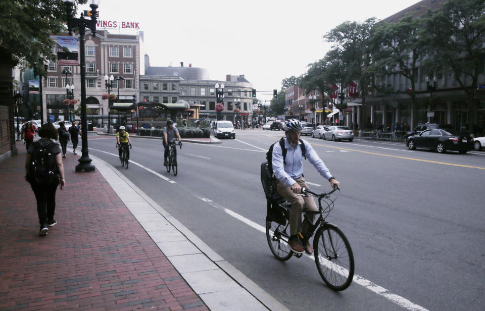 FILE - In this Aug. 13, 2019, file photo, a bicyclist rides on a bike lane through Harvard Square in Cambridge, Mass. A government agency is recommending that all 50 states enact laws requiring bicyclists to wear helmets to stem an increase in bicycle deaths on U.S. roadways. The recommendation was among several issued by the National Transportation Safety Board after a hearing Tuesday, Nov. 5, on bicycle safety. (AP Photo/Charles Krupa, File)