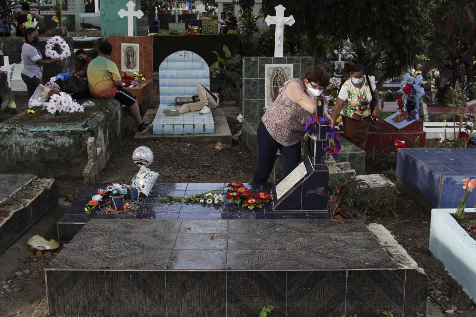 A woman places flowers at the tomb of her relative, next to one of the graves of a gang member whose tombstone was destroyed on the order of the government, during the Day of the Dead at the Nueva San Salvador Cemetery, in Santa Tecla, El Salvador, Wednesday, Nov. 2, 2022. Santa Tecla Mayor Henry Flores said the crews had destroyed nearly 80 tombstones in the municipal cemetery and erased gang-related graffiti. (AP Photo/Salvador Melendez)