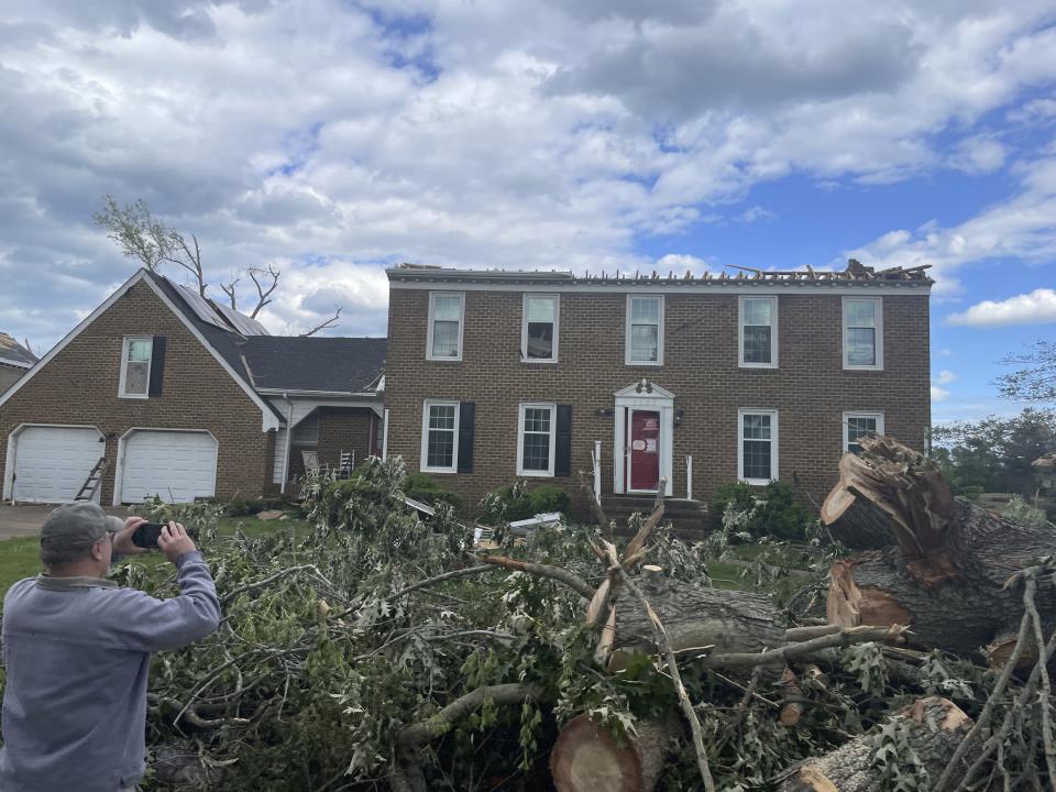 A man photographs a home damaged by a tornado in Virginia Beach, Va., on Monday May 1, 2023. (AP Photo/John C. Clark)