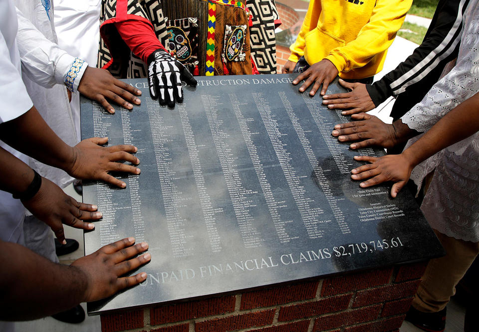 Members of the African Ancestral Society touch the 1921 Black Wall Street Memorial during the Black Wall Street Memorial March in Tulsa on May 28, 2021.<span class="copyright">Mike Simons—Tulsa World/AP</span>