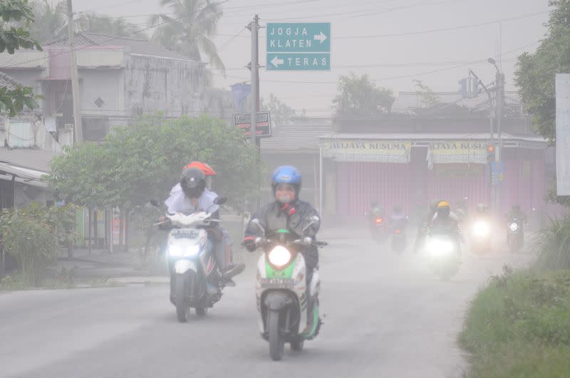 Motorists ride their motorbikes along a road engulfed with ash following the eruption of Mount Merapi volcano in Boyolali