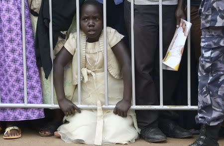 A child kneels behind a barrier as Pope Francis leads a mass in Kampala, Uganda, November 28, 2015. REUTERS/Stefano Rellandini