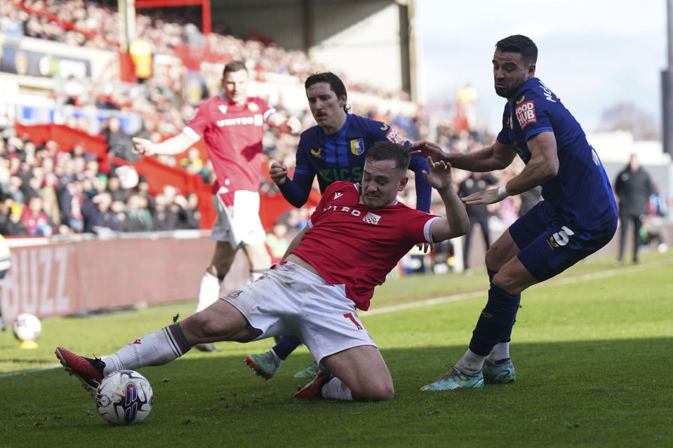 Wrexham's Luke Bolton, centre, challenges for the ball with Mansfield Town's Stephen McLaughlin during the English League Two soccer match between Wrexham and Mansfield Town at the SToK Cae Ras in Wrexham, Wales, Friday, March 29, 2024. (Jacob King/PA via AP)