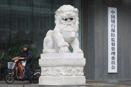 A man rides an electric bike past the CBIRC building in Beijing