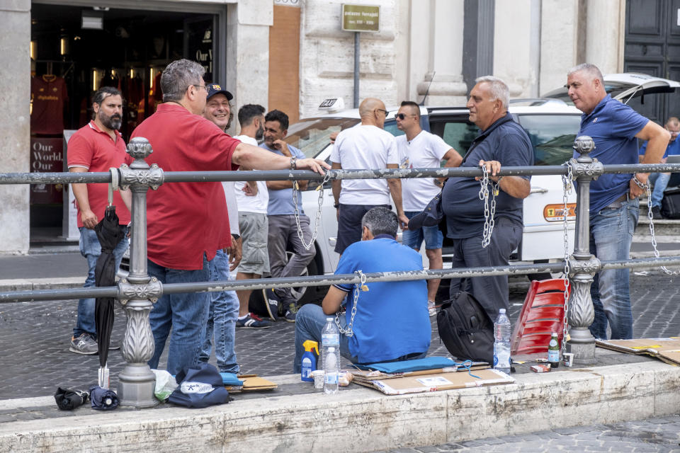 Taxi drivers are chained together in protest in the square outside Premier Mario Draghi’s office in Rome, Wednesday, July 13, 2022, on their second day of protest against the Italian government's plans to allow more competition, including share-ride services. (Mauro Scrobogna /LaPresse via AP)