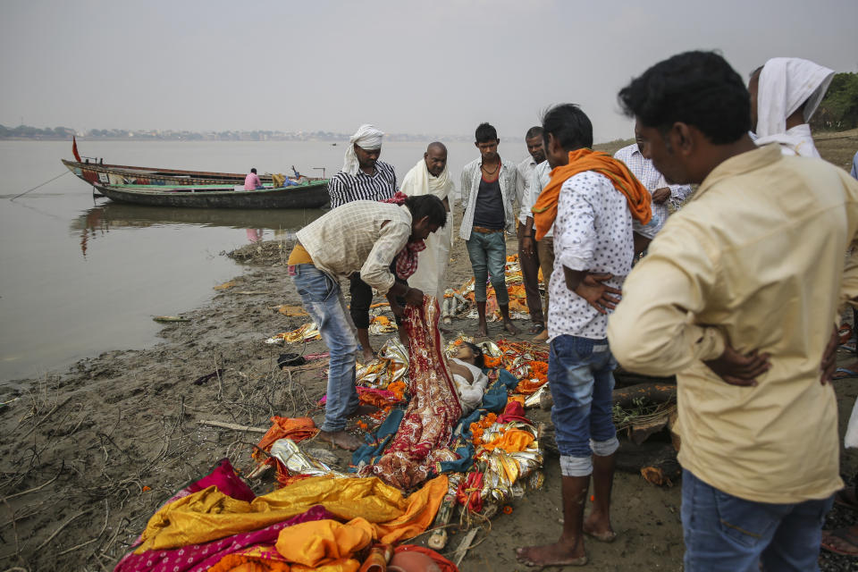 People prepare to cremate the body of a Hindu woman on the banks of the river Ganges on the outskirts of Varanasi, one of the Hinduism's holiest cities, India, Thursday, Oct. 17, 2019. For millions of Hindus, Varanasi is a place of pilgrimage and anyone who dies in the city or is cremated on its ghats is believed to attain salvation and freed from the cycle of birth and death. Tens of thousands of corpses are cremated in the city each year, leaving half-burnt flesh, dead bodies and ash floating in the Ganges. (AP Photo/Altaf Qadri)