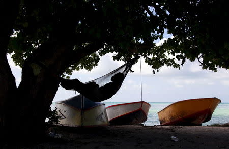 A man sleeps in a hammock next to fishing boats in the town of Bairki on South Tarawa in the central Pacific island nation of Kiribati in this May 23, 2013 file photo. REUTERS/David Gray/Files
