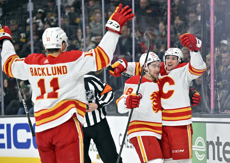 Calgary Flames center Mikael Backlund (11), left wing Andrew Mangiapane (88) and left wing Jakob Pelletier, right, celebrate after Pelletier's goal against the Vegas Golden Knights during the first period of an NHL hockey game Thursday, Feb. 23, 2023, in Las Vegas. (AP Photo/David Becker)