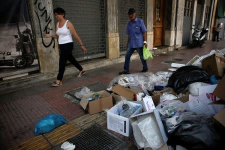 People walk past a pile of garbage in Piraeus, near Athens, Greece June 26, 2017. REUTERS/Alkis Konstantinidis