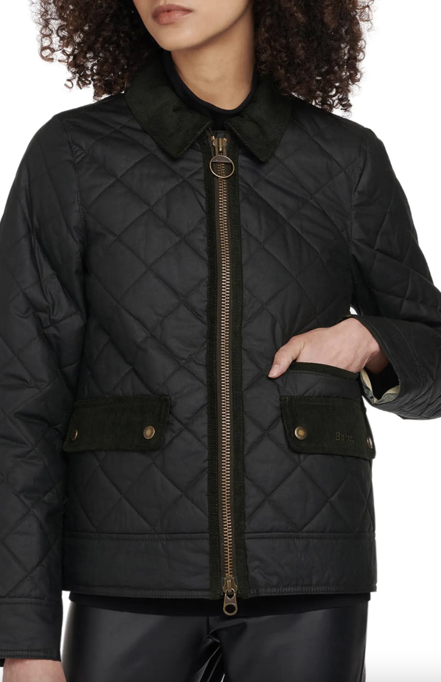 model with curly hair in black Barbour Helmsdale Quilted Waxed Cotton Raincoat (Photo via Nordstrom)