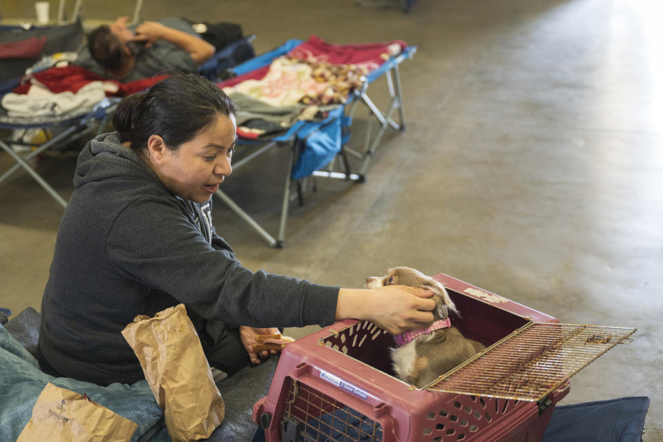 Anais Rodriguez comforts her dog, Mile, at an evacuation center at Santa Cruz County fairgrounds in Watsonville, Calif., Saturday, March 11, 2023. They were evacuated from their Pajaro home on Saturday morning. (AP Photo/Nic Coury)