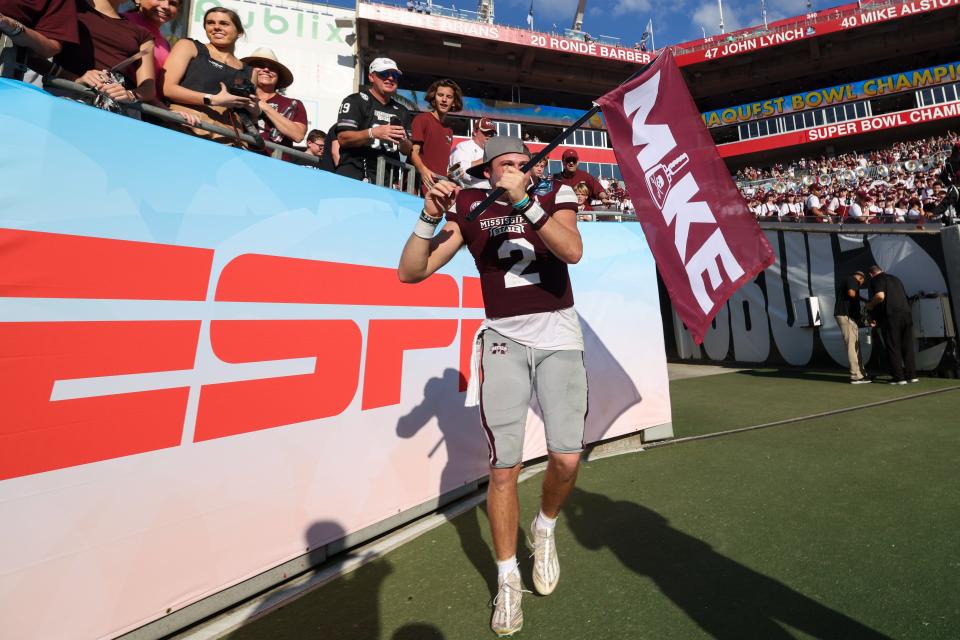 Mississippi State quarterback Will Rogers (2) celebrates with a flag honoring former coach Mike Leach after the Bulldogs defeated Illinois in the ReliaQuest Bowl at Raymond James Stadium.