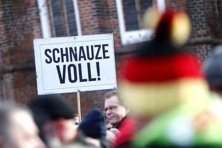 A man holds a placard during the demonstration against migrants in Cottbus, Germany February 3, 2018. Sign reads "Fed up!". REUTERS/Hannibal Hanschke