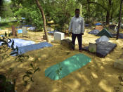 A relative stands next to the grave of Dr. Jibraeil, assistant professor of history at Aligarh Muslim Uliversity, who died of COVID-19, in Aligarh, India, Saturday, June 12, 2021. Within just one month, the official Facebook page of Aligarh Muslim University, one of the topmost in India, published about two dozen obituaries of its teachers, all lost to the pandemic. Across the country, the deaths of educators during the devastating surge in April and May have left students and staff members grief-stricken and close-knit university communities shaken. (AP Photo/Manoj Aligadi)