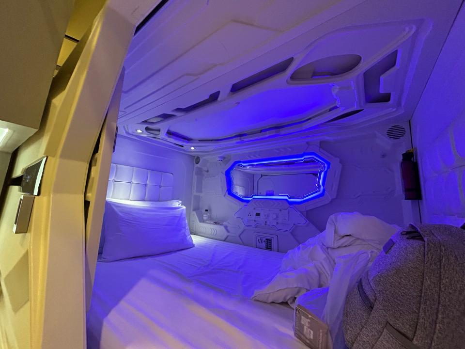 A twin-sized bed is shown inside a sleeping pod.