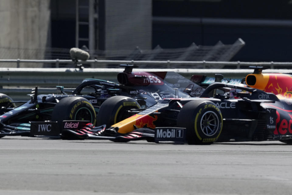 El británico Lewis Hamilton, izquierda, de Mercedes, y el holandés Max Verstappen, de Red Bull, toman una curva mientras pelean por la punta al inicio del Gran Premio Británico de la Fórmula Uno, en el circuito de Silverstone, Inglaterra, el domingo 18 de julio de 2021. (AP Foto/Jon Super)