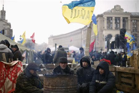 Protesters warm up near a barricade at Independence Square in Kiev December 7, 2013. REUTERS/Stoyan Nenov