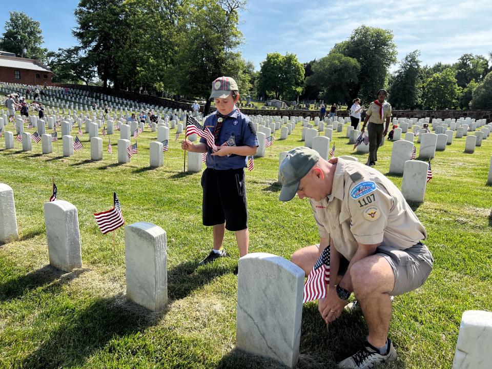 Volunteers place flags on graves at  Alexandria National Cemetery Saturday.