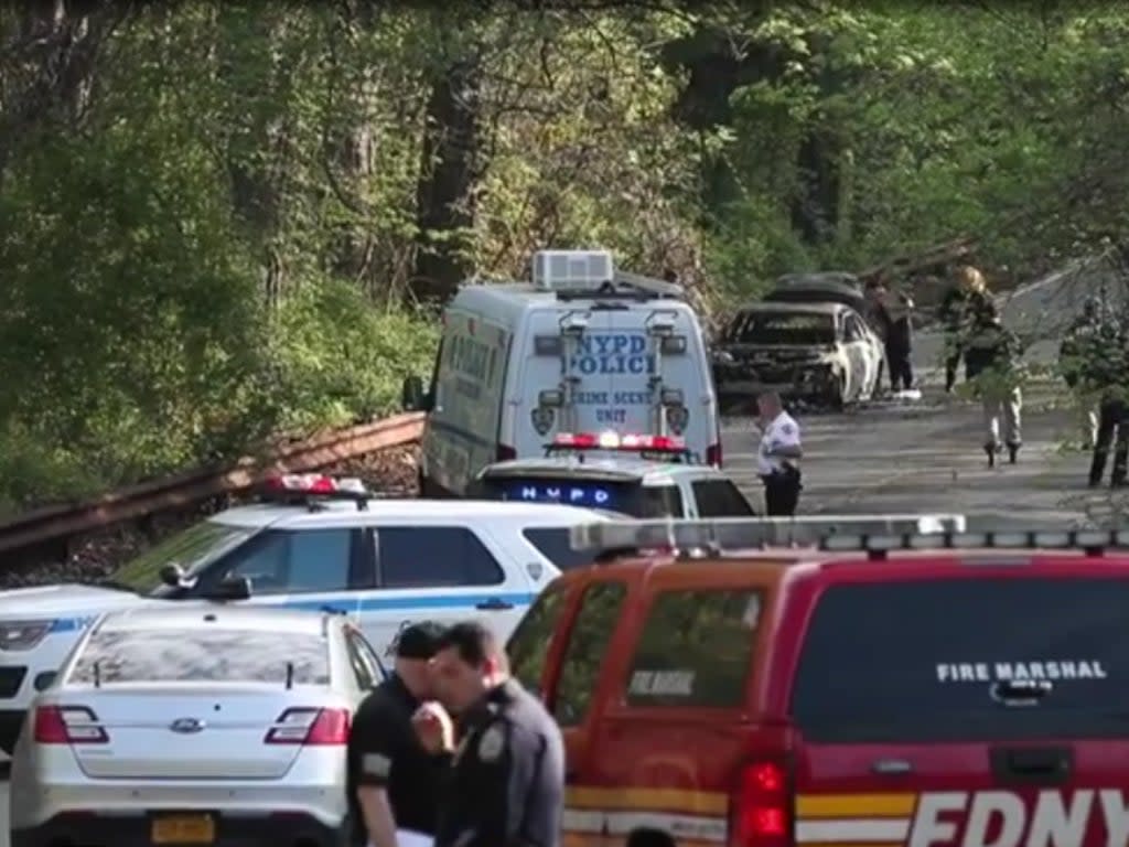 Image shows police officers near the site in Bronx where the burnt car with the dead couple was found on Monday, 16 May 2022 (Screengrab/New York Post)