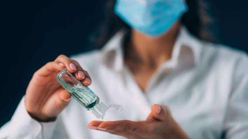 Young woman disinfecting her hands using hand sanitizer gel. 