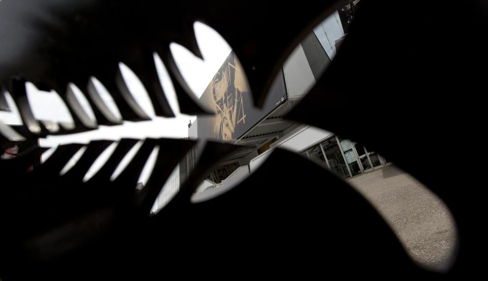 The official Cannes Film Festival poster which features Marcello Mastroianni and is based on the Federico Fellini movie "8 1/2" is taken through a metal logo of the Cannes Film Festival in Cannes, France on Monday, May 12, 2014. The Festival will run from May 14-25th. (AP Photo/Virginia Mayo)