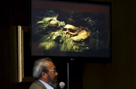 Raul Barrera, an archaeologist from the National Institute of Anthropology and History (INAH), speaks to the media as a picture of a skull that was discovered at the ruins of the Templo Mayor Aztec complex is seen above him, during a news conference at the Anthropology Museum in Mexico City August 20, 2015. REUTERS/Henry Romero