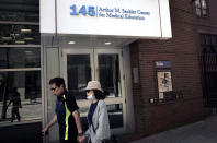 In this Sept. 25, 2019, photo, passers-by walk near an entrance to Tufts School of Medicine in Boston. Some universities’ ties to the Sackler family have come under fire recently, including in a 2018 lawsuit from the Massachusetts attorney general arguing that Purdue Pharma used its influence at Tufts University and other schools to promote opioids. (AP Photo/Steven Senne)