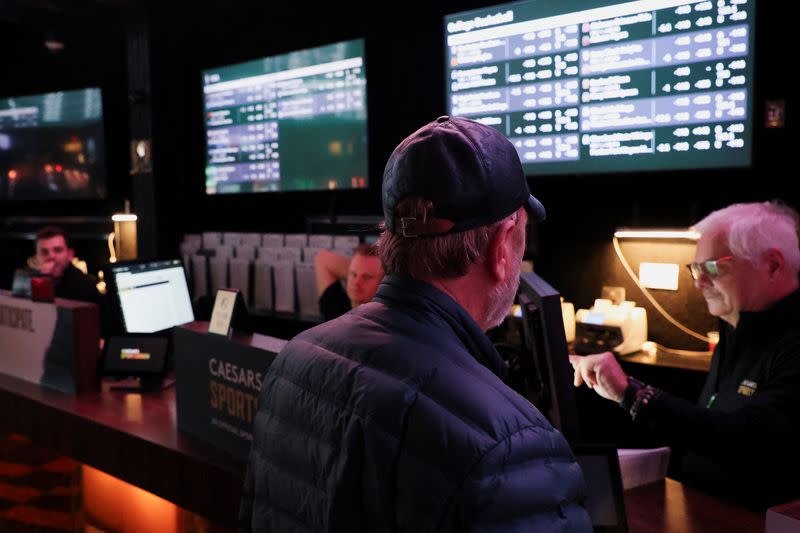 A man speaks with a cashier at the sportsbook area of Caesars Palace, in Las Vegas