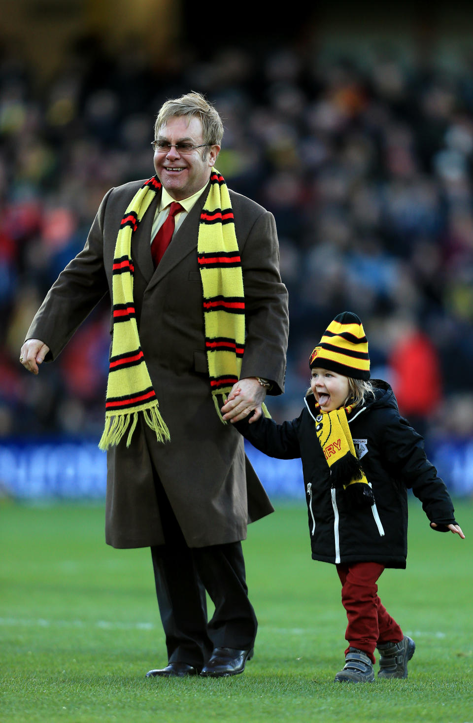 Elton and his son walking on a football field