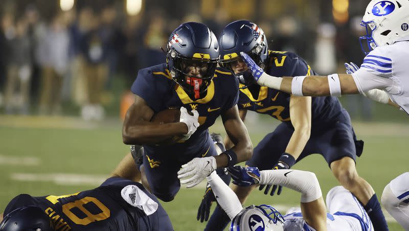 West Virginia’s Traylon Ray, top, jumps over players during the first half of an NCAA college football game against BYU on Saturday, Nov. 4, 2023, in Morgantown, W.Va. 