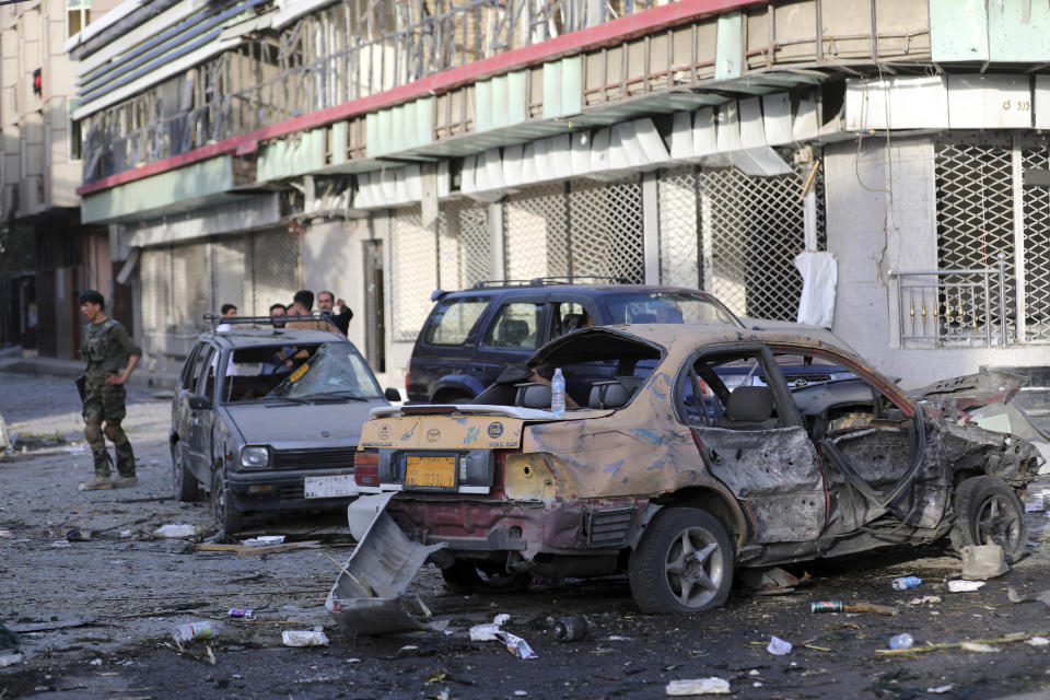 An Afghan national army soldier, left, stands guard near debris following an attack in Kabul, Afghanistan, Wednesday, Aug. 4, 2021. A powerful explosion rocked an upscale neighborhood of Afghanistan's capital Tuesday in an attack that apparently targeted the country's acting defense minister. (AP Photo/Rahmat Gul)