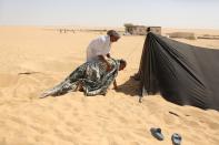 A worker helps a patient covered with a blanket to go to a sauna-like tent after he was removed from the hot sands where he was buried in Siwa, Egypt, August 12, 2015. (REUTERS/Asmaa Waguih)