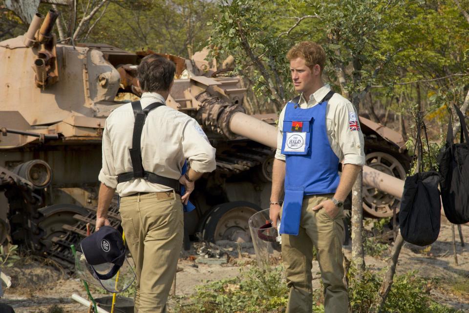 In this handout photo made available by the HALO Trust on Saturday, Aug. 17, 2013, Britain's Prince Harry, right, speaks with HALO Director Guy Willougby as they stand near a South African Olifant tank destroyed in the Battle of Cuito Cuanavale in 1988, in Angola. Harry returned from Angola, where he visited a landmine clearance charity championed by his late mother, Princess Diana. The HALO Trust charity said Saturday the 28-year-old prince visited the Angolan town of Cuito Cuanavale, which saw heavy fighting during the southern African nation’s 1975-2002 civil war. The group said Harry toured minefields and met beneficiaries of the group’s work. (AP Photo/HALO Trust)