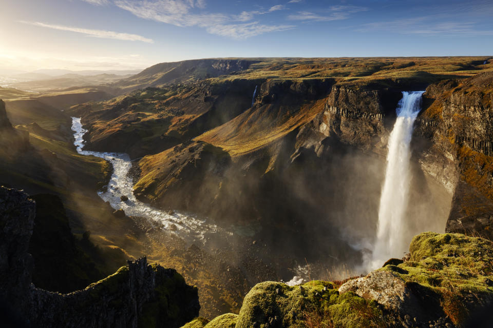 Waterfall cascading into a river within a scenic, rocky landscape